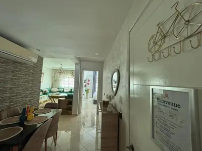 a dining room and living room with a bike on the wall at Chez A&J, appartement climatisé, proche du Stade de Rabat in Temara