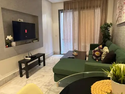 a living room with a green couch and a flat screen tv at Modern studio with large terrace and parking in Casablanca