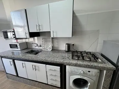 a kitchen with a stove and a washing machine at studio ensoleillé á louer Témara, in Temara