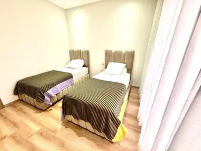 two beds in a room with white walls and wooden floors at Hideaway Rosa Parc Mohammedia in Mohammedia