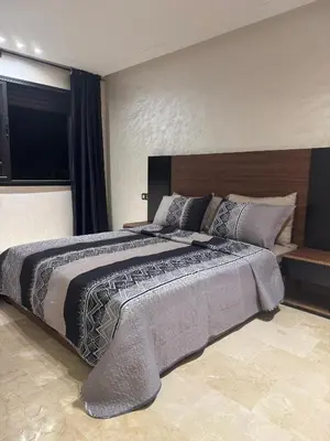 a bedroom with a large bed with a wooden headboard at Studio au parc calme in Mohammedia