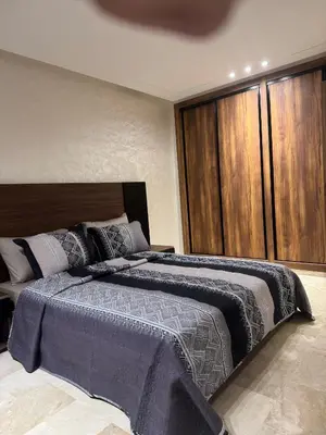 a bedroom with a large bed with a wooden headboard at Studio au parc calme in Mohammedia