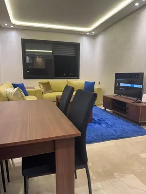 a living room with a table and a couch and a television at Studio au parc calme in Mohammedia