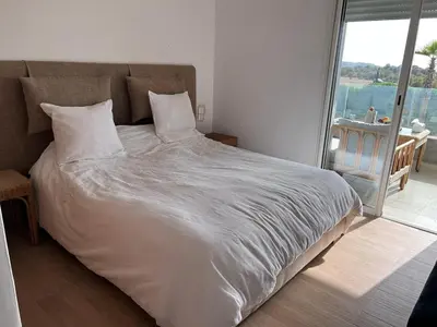 a bed in a bedroom with a large window at Sidi Rahal Blue View 3, front mer, accès plage 1 Piscine in Sidi Rahal