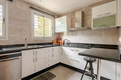 a kitchen with white cabinets and a black counter top at Villa Evasion Rabat Beach in Rabat