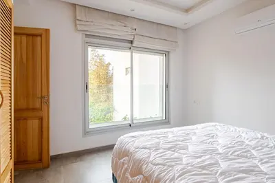 a white bedroom with a bed and a window at Villa Evasion Rabat Beach in Rabat