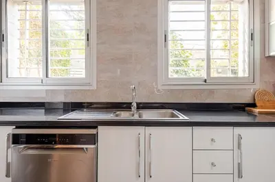 a kitchen with white cabinets and a sink and two windows at Villa Evasion Rabat Beach in Rabat