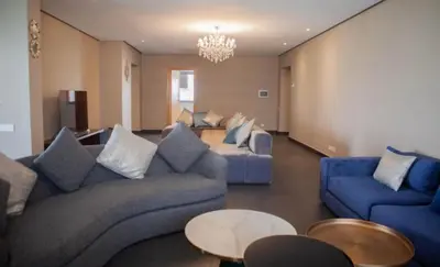 a living room with blue couches and a chandelier at Appartement entier 2 chambres marina avec vue panoramique mer in Casablanca