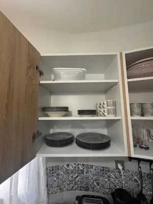 a kitchen with plates and bowls on shelves at Appartement Casablanca près de la mer in Dar Bouazza