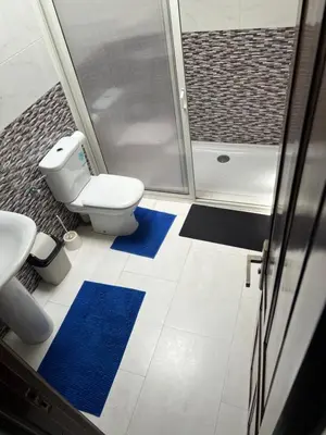 a bathroom with a toilet and a shower and blue mats at Chez Bouchra in Mansouria
