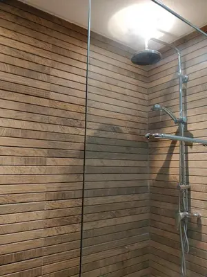 a bathroom with a shower with a wooden wall at Beautiful, Bright and modern 3 bedroom apartment in Casablanca