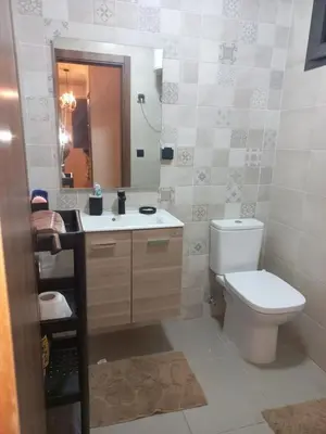 a bathroom with a toilet and a sink and a mirror at Bel appartement près de la plage pour Famille in El Harhoura