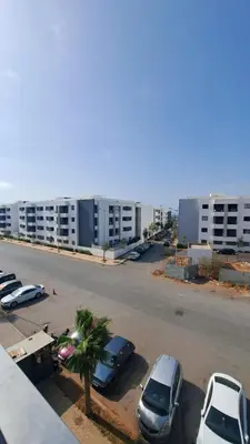 a parking lot with cars parked in front of a building at Bel appartement près de la plage pour Famille in El Harhoura