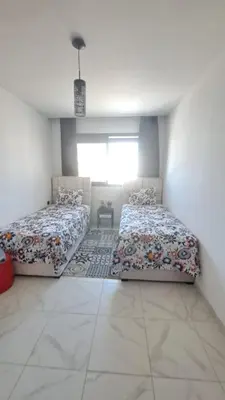 a bedroom with two beds and a window at Bel appartement près de la plage pour Famille in El Harhoura
