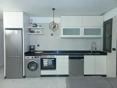 a kitchen with a refrigerator and a washing machine at Bel appartement près de la plage pour Famille in El Harhoura
