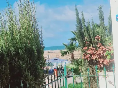 a beach with a fence and trees and the ocean at Résidence marbella mansouria in Mansouria