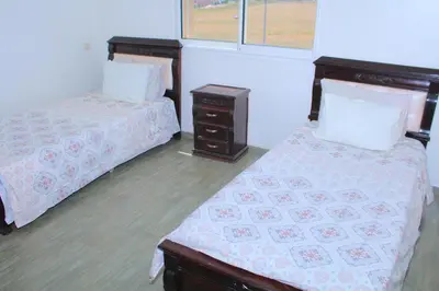 a bedroom with two beds and a night stand and a window at Bouznika H18 in Bouznika