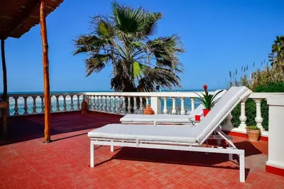 a white lounge chair on a deck with a palm tree at Grande villa luxueuse face à l'Océan in Temara