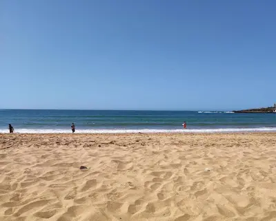 a beach with people walking on the sand and the ocean at Ricoflores Mansouria in Mansouria