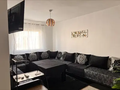a living room with a black couch and a table at BOUZNIKA PLAGe in Bouznika