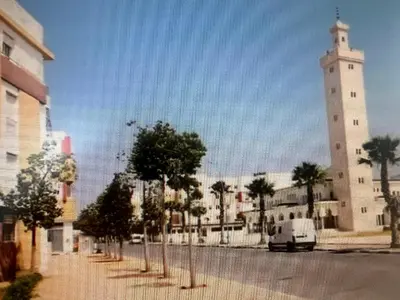 a street with a white tower and a white van at BOUZNIKA PLAGe in Bouznika