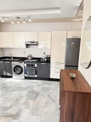 a large kitchen with white cabinets and a wooden table at Luxury Beachview Apartment La siesta beach resort in Mohammedia