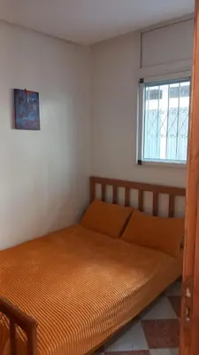 an orange bed in a room with a window at Le Refuge in Temara