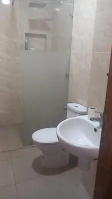 a white bathroom with a toilet and a sink at Le Refuge in Temara