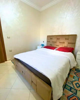 a bedroom with a large white bed with red pillows at Appartement Calme à Mohammadia - Séjour Agréable in Mohammedia
