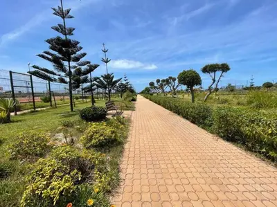 a brick path in a park with a bench and trees at appartement ola blanca 2 in Dar Hamida
