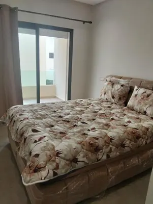 a large bed in a bedroom with a large window at Appartement avec piscine El mansoria Mohammedia in Mansouria