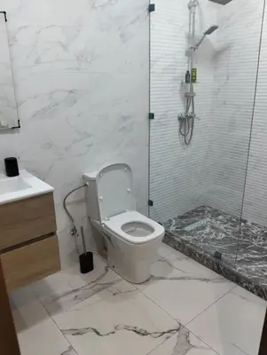 a white bathroom with a toilet and a shower at Appartement avec piscine El mansoria Mohammedia in Mansouria