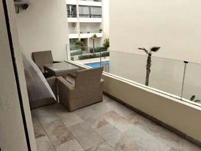 a balcony with chairs and a table and a palm tree at Appartement avec piscine El mansoria Mohammedia in Mansouria