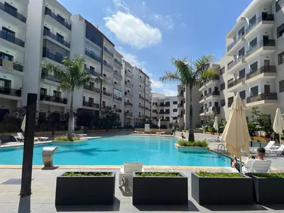 a swimming pool in front of a large building at Elegant & Cozy Beach Apartment in Mohammedia