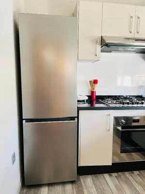 a stainless steel refrigerator in a kitchen with white cabinets at Elegant & Cozy Beach Apartment in Mohammedia