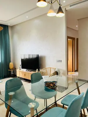 a living room with blue chairs and a television at Elegant & Cozy Beach Apartment in Mohammedia