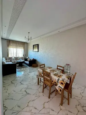 a living room with a table and chairs on a marble floor at Appartement haut standing, 2 chambres - Mohammedia in Mohammedia