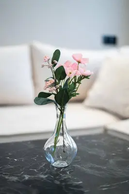 a glass vase with pink flowers on a table at Appart familial cœur Casa in Casablanca