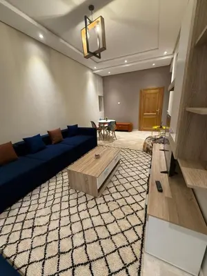 a living room with a blue couch and a table at Studio Perla Sofé in Nouaseur