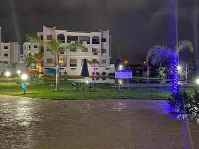 a park at night with blue lights in front of a building at Yasmine Beach in Mansouria