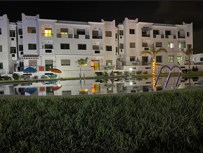 a large white building with a pool in front of it at Yasmine Beach in Mansouria