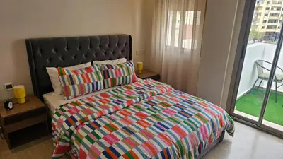 a bedroom with a bed with a colorful comforter and a window at Bright 2BR Apartment in Maârif, Ideal for Families & Business Travelers in Casablanca