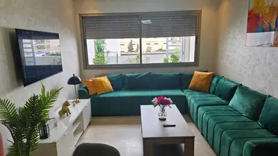 a living room with a green couch and a table at Bright 2BR Apartment in Maârif, Ideal for Families & Business Travelers in Casablanca