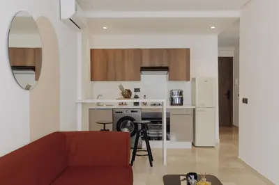 a living room with a red couch and a kitchen at The Shelter Residence by GoodMove - Bourgogne, Casablanca in Casablanca