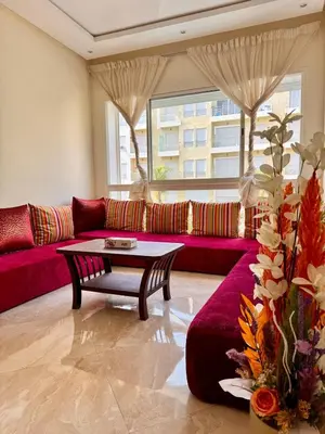 a living room with a red couch and a table at Bright Apt with Balcony, WiFi, Parking and Pool Resort in Bouznika