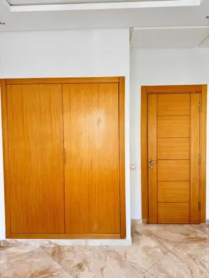 two wooden doors in a white room with marble floors at Bright Apt with Balcony, WiFi, Parking and Pool Resort in Bouznika