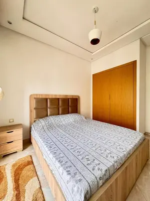 a bedroom with a large bed and a wooden headboard at Bright Apt with Balcony, WiFi, Parking and Pool Resort in Bouznika