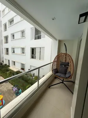 a wicker chair sitting on a balcony with a window at Plage manesmann in Mohammedia