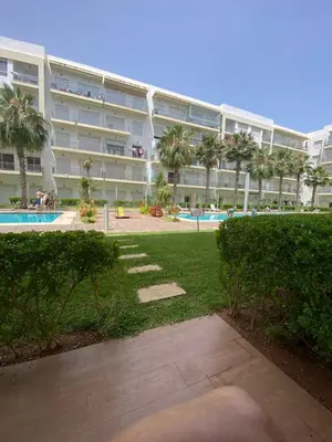 a large apartment building with a swimming pool and palm trees at Appartement de haut standing,4 piscines in Bouznika