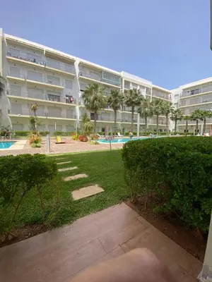 a large apartment building with a lawn in front of it at Appartement de haut standing,4 piscines in Bouznika
